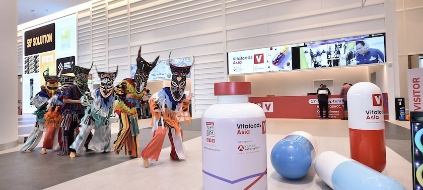 Three attendees at Vitafood Asia engage in friendly conversation